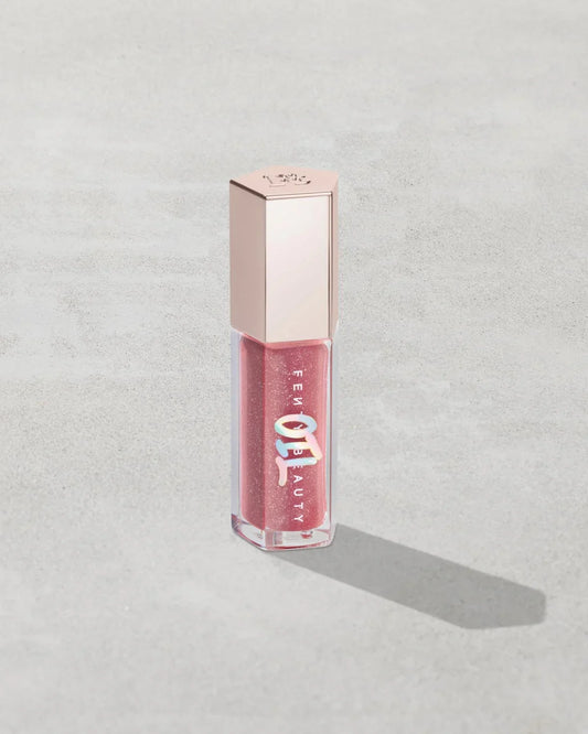 Shimmery pink lip gloss in clear tube with metallic cap on a light gray background